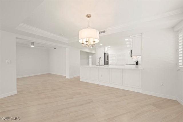 unfurnished dining area with a chandelier, ornamental molding, light wood-style floors, baseboards, and a sink