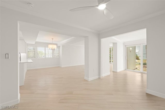 spare room with a chandelier, light wood-style flooring, crown molding, ceiling fan, and baseboards