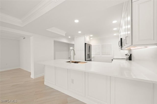 kitchen with appliances with stainless steel finishes, a sink, a peninsula, recessed lighting, and light countertops