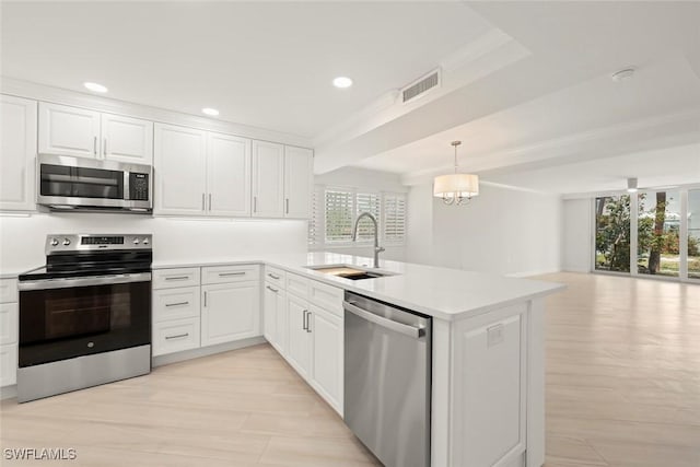 kitchen with stainless steel appliances, a sink, a peninsula, light countertops, and open floor plan