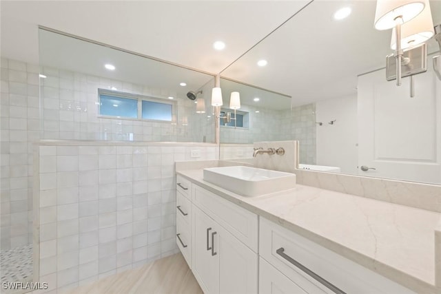 full bathroom with walk in shower, tile walls, vanity, and recessed lighting