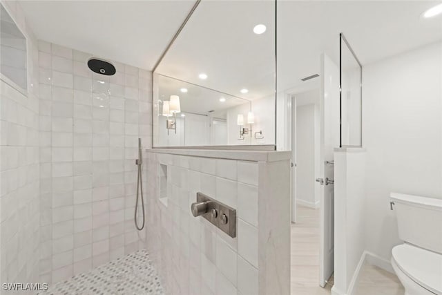 bathroom with a tile shower, recessed lighting, toilet, and baseboards