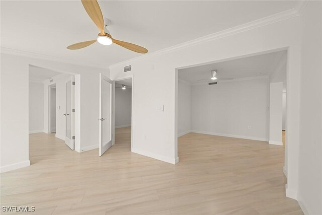 spare room with a ceiling fan, crown molding, light wood-style flooring, and baseboards