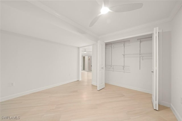 unfurnished bedroom with light wood-type flooring, ornamental molding, baseboards, a closet, and a ceiling fan