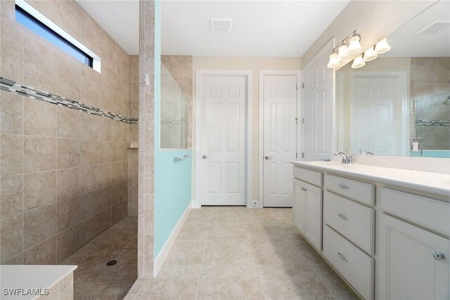 full bath with vanity, visible vents, baseboards, and walk in shower