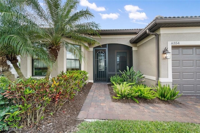 entrance to property featuring a garage and stucco siding