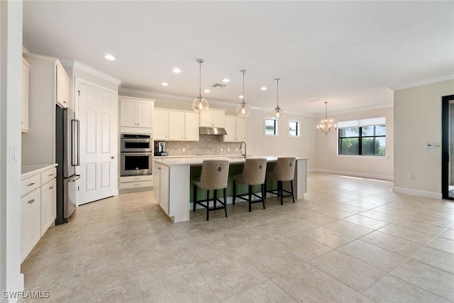 kitchen featuring decorative backsplash, light countertops, appliances with stainless steel finishes, under cabinet range hood, and an inviting chandelier