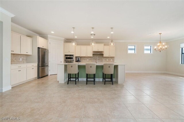 kitchen with a center island with sink, appliances with stainless steel finishes, under cabinet range hood, an inviting chandelier, and a kitchen breakfast bar