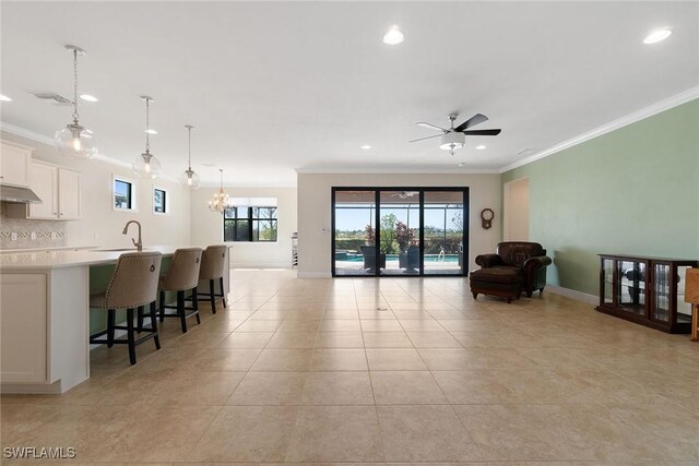interior space with a wealth of natural light, crown molding, ceiling fan with notable chandelier, and light tile patterned floors