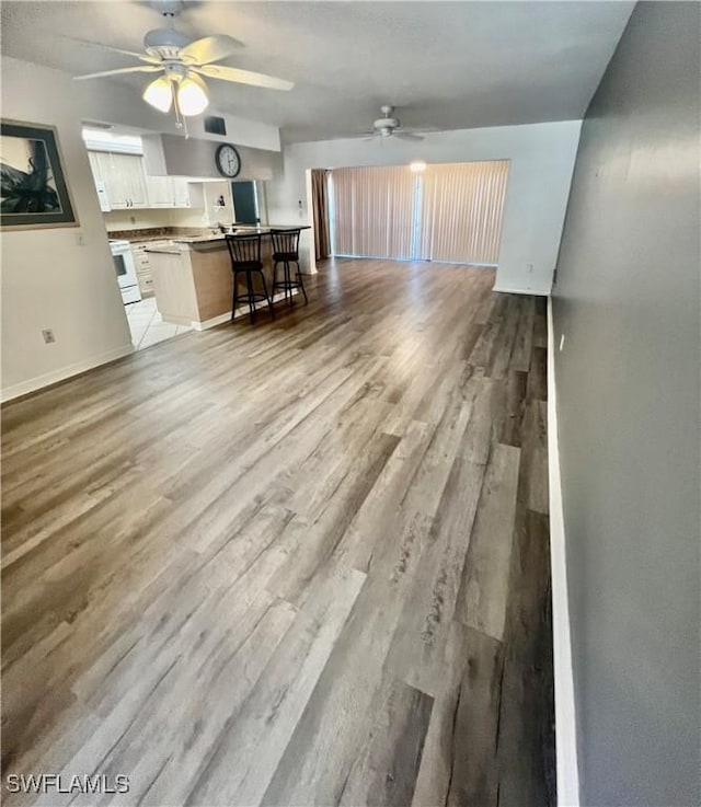 5765 Trailwinds Dr Unit 115, Fort Myers, FL 33907 - unfurnished living room featuring a ceiling fan, baseboards, and light wood-style flooring