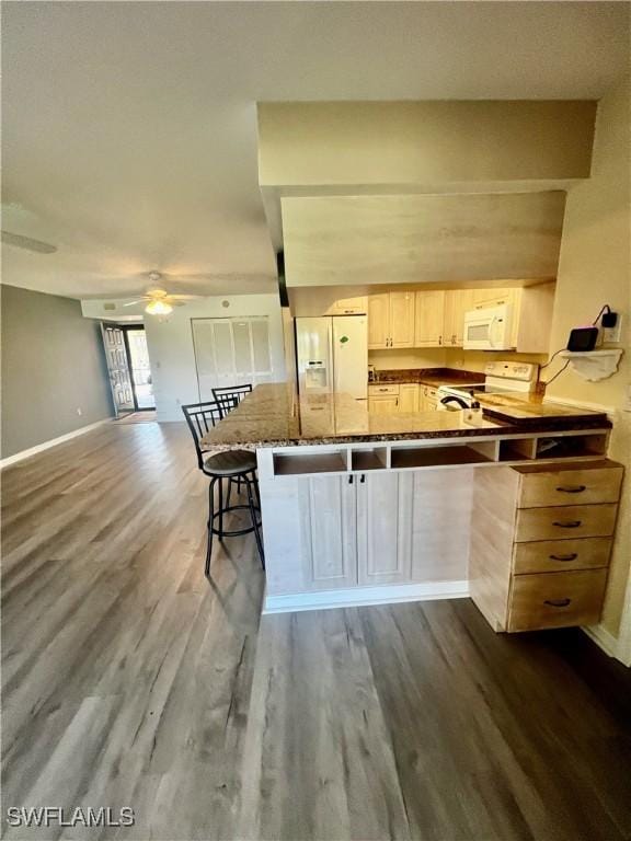 5765 Trailwinds Dr Unit 115, Fort Myers, FL 33907 - kitchen with white appliances, dark wood-style flooring, a ceiling fan, a breakfast bar, and baseboards