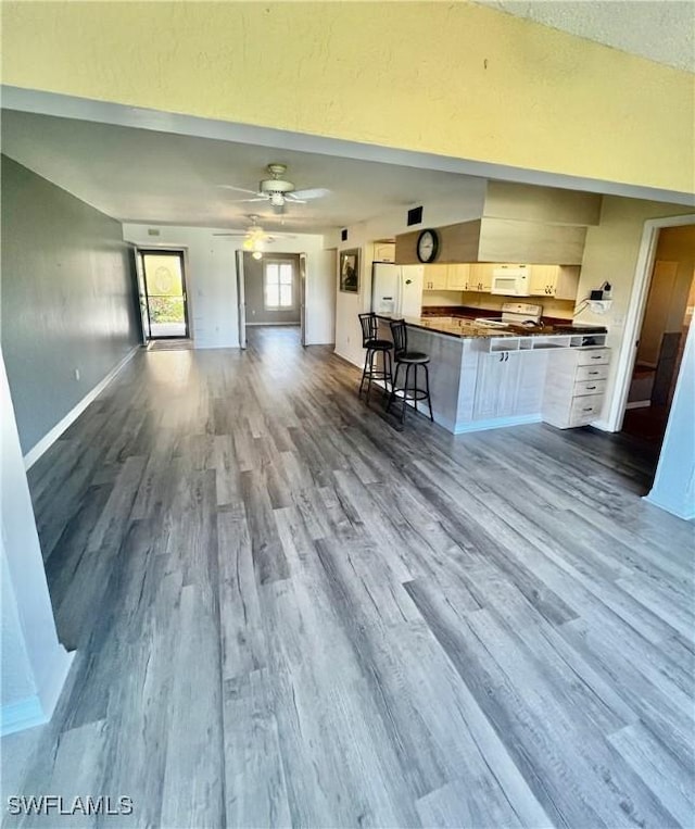 5765 Trailwinds Dr Unit 115, Fort Myers, FL 33907 - kitchen featuring open floor plan, dark wood-type flooring, dark countertops, white appliances, and a kitchen bar