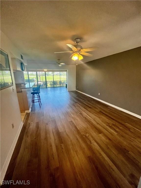 5765 Trailwinds Dr Unit 115, Fort Myers, FL 33907 - unfurnished living room featuring dark wood-style flooring, baseboards, a textured ceiling, and ceiling fan