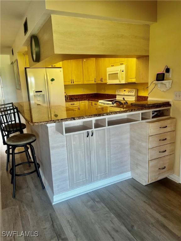 5765 Trailwinds Dr Unit 115, Fort Myers, FL 33907 - kitchen with white appliances, dark wood-style flooring, dark stone countertops, and a peninsula