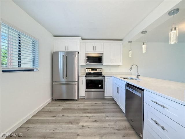 kitchen featuring appliances with stainless steel finishes, light countertops, light wood finished floors, a sink, and white cabinetry
