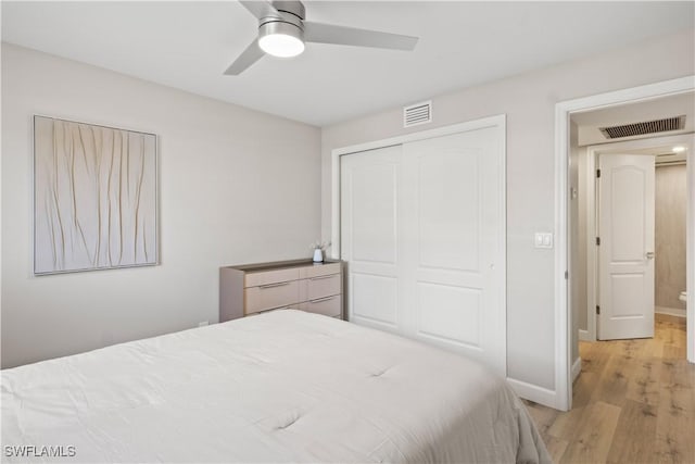 bedroom with baseboards, visible vents, a closet, and wood finished floors