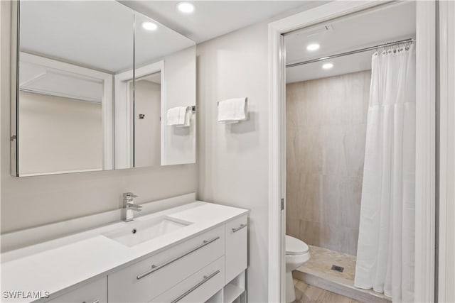 bathroom featuring toilet, vanity, a tile shower, and recessed lighting