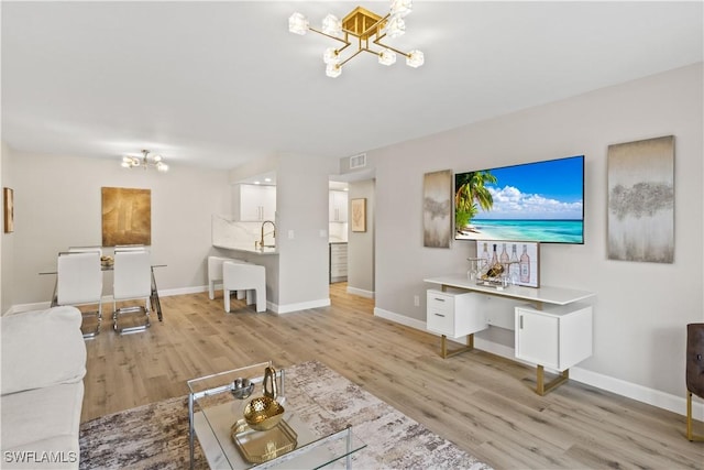 living room with baseboards, light wood-style floors, and a chandelier