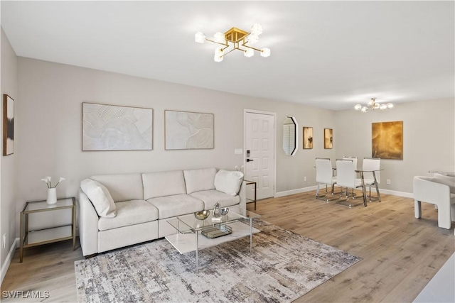 living area featuring baseboards, a notable chandelier, and light wood-style flooring