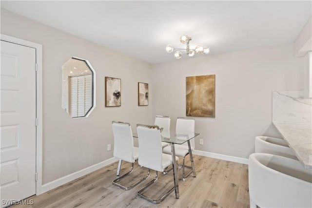 dining space featuring baseboards, a notable chandelier, and light wood-style flooring