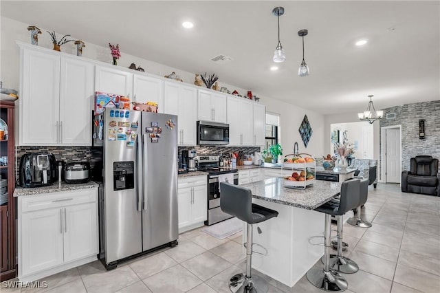 4558 Lamaida Ln, Ave Maria, FL 34142 - kitchen with a breakfast bar area, visible vents, tasteful backsplash, and appliances with stainless steel finishes