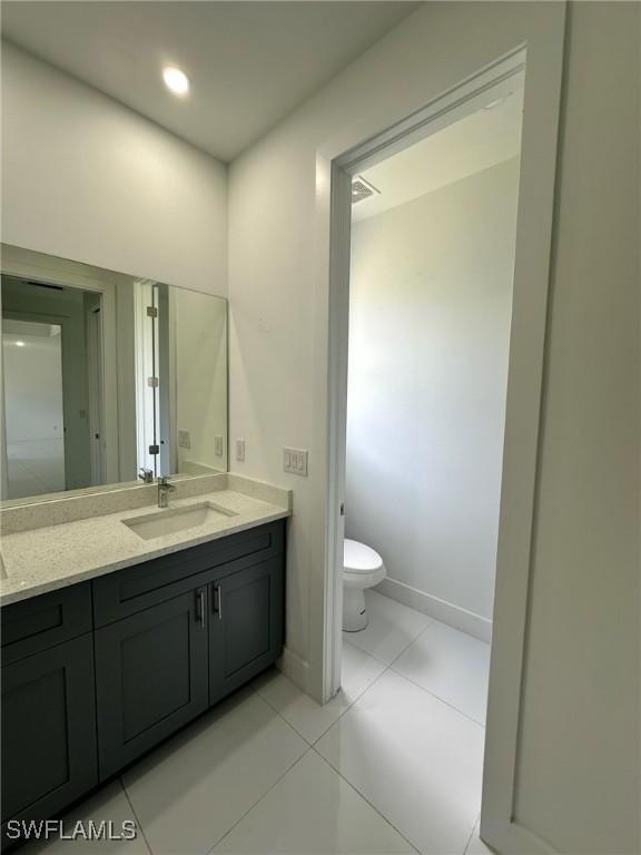 718 Chattman St E, Lehigh Acres, FL 33974 - bathroom with baseboards, vanity, toilet, and tile patterned floors