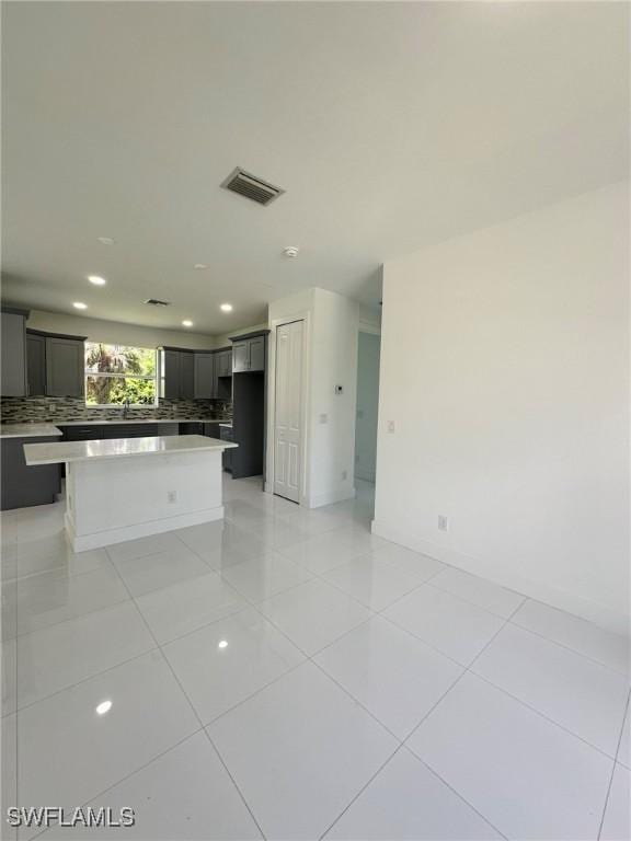 718 Chattman St E, Lehigh Acres, FL 33974 - kitchen with backsplash, light countertops, light tile patterned floors, recessed lighting, and a center island