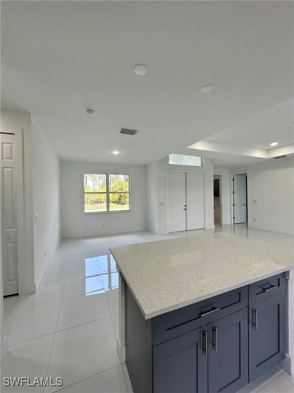 718 Chattman St E, Lehigh Acres, FL 33974 - kitchen featuring open floor plan, light stone counters, light tile patterned floors, a center island, and baseboards