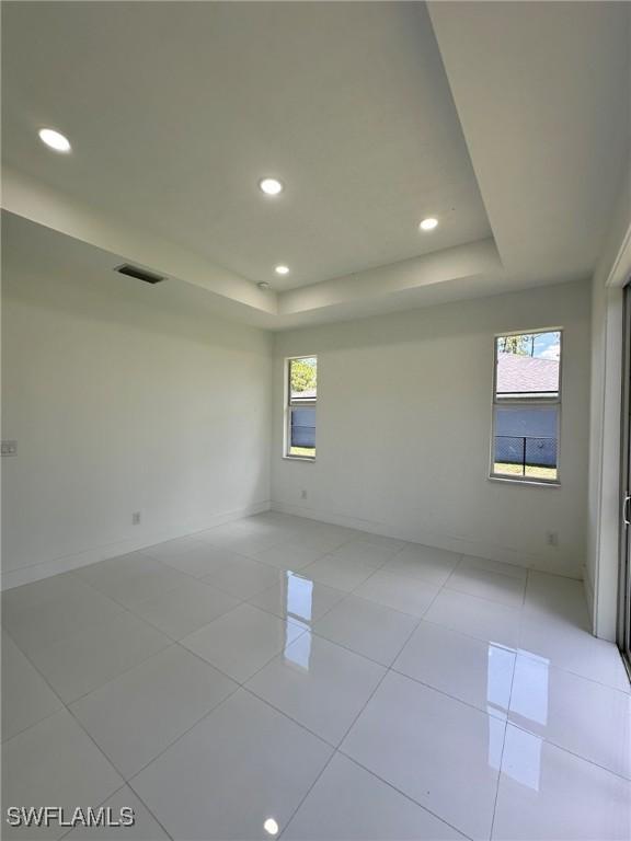 718 Chattman St E, Lehigh Acres, FL 33974 - unfurnished room featuring a raised ceiling, recessed lighting, light tile patterned flooring, and baseboards