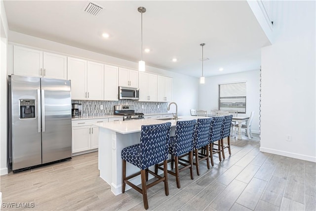 18707 Ivywood Pl, Estero, FL 33928 - kitchen featuring visible vents, white cabinets, an island with sink, stainless steel appliances, and decorative backsplash