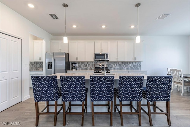 18707 Ivywood Pl, Estero, FL 33928 - kitchen with an island with sink, white cabinetry, light countertops, and appliances with stainless steel finishes