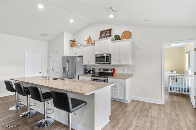 490 Windermere Dr, Lehigh Acres, FL 33972 - kitchen featuring a sink, a kitchen bar, a center island with sink, stainless steel appliances, and white cabinets