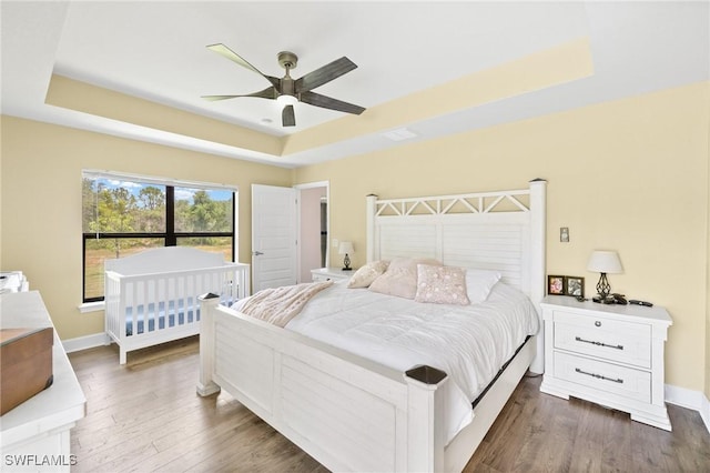 490 Windermere Dr, Lehigh Acres, FL 33972 - bedroom featuring a tray ceiling, dark wood-style floors, baseboards, and a ceiling fan