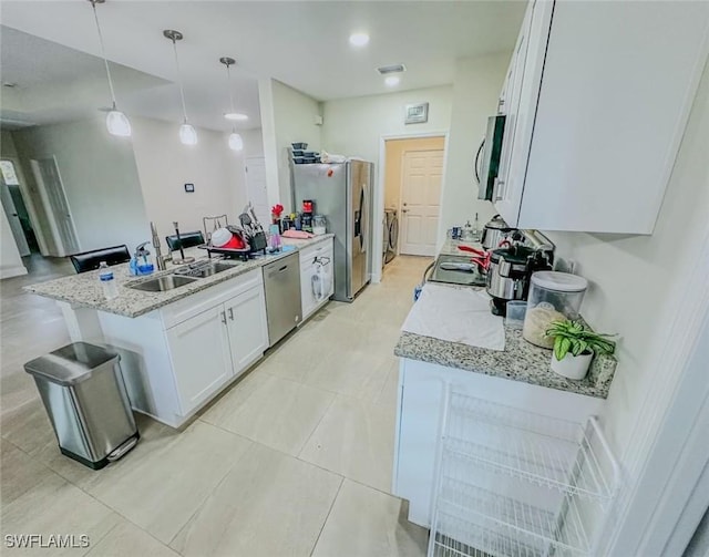 kitchen with decorative light fixtures, a sink, a peninsula, stainless steel appliances, and white cabinetry
