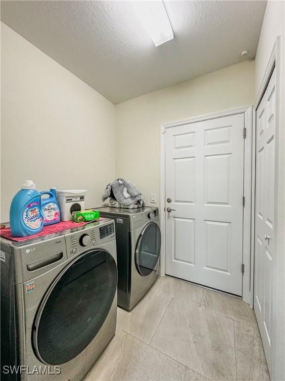washroom with laundry area, washer and clothes dryer, and a textured ceiling