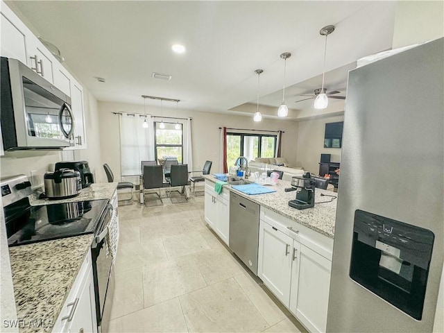 kitchen featuring a ceiling fan, decorative light fixtures, light stone counters, white cabinets, and stainless steel appliances