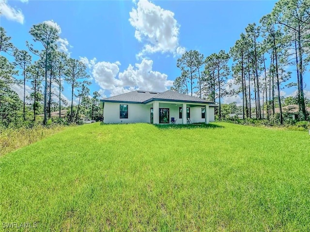 back of property featuring a lawn and stucco siding