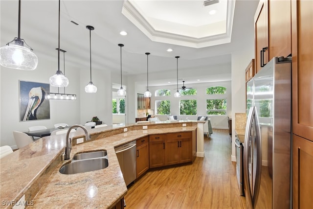 27549 Riverbank Dr, Bonita Springs, FL 34134 - kitchen featuring a sink, brown cabinets, a tray ceiling, stainless steel appliances, and light wood-style flooring