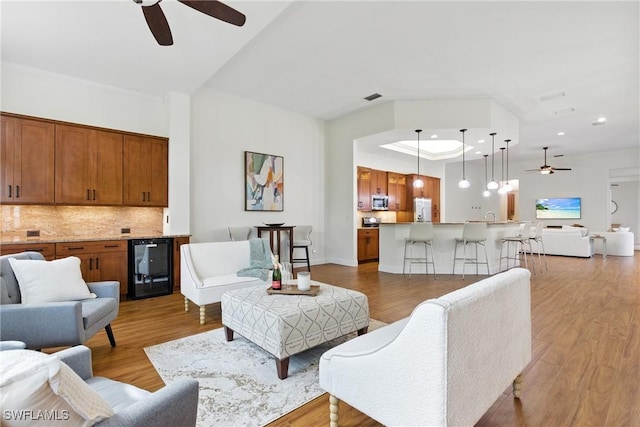 27549 Riverbank Dr, Bonita Springs, FL 34134 - living room with visible vents, ceiling fan, a tray ceiling, light wood-style flooring, and beverage cooler