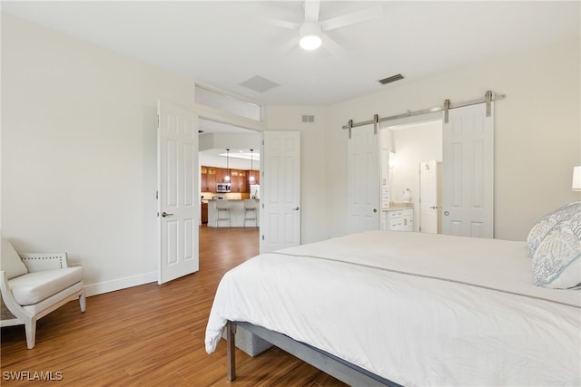 27549 Riverbank Dr, Bonita Springs, FL 34134 - bedroom with visible vents, baseboards, a barn door, and wood finished floors