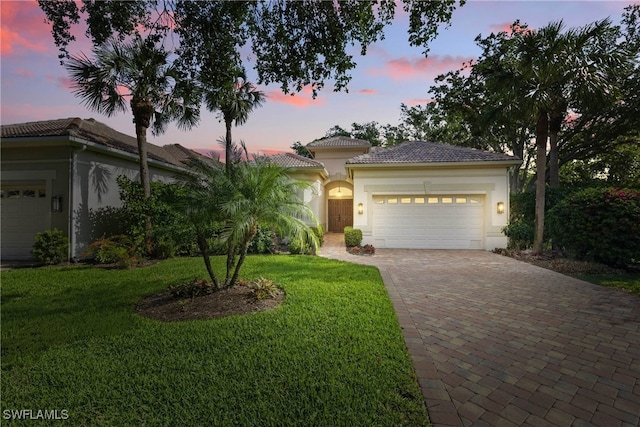 27549 Riverbank Dr, Bonita Springs, FL 34134 - view of front of home with a tiled roof, a yard, an attached garage, stucco siding, and decorative driveway