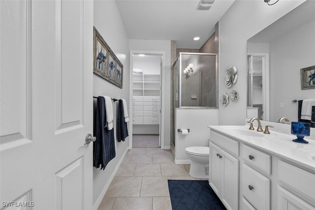 full bathroom featuring a stall shower, tile patterned floors, toilet, vanity, and a walk in closet