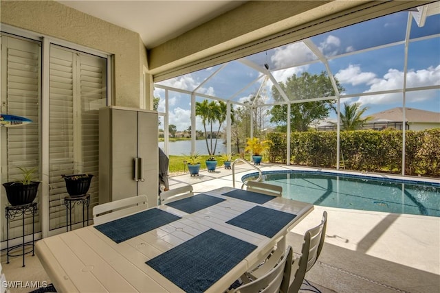 view of swimming pool with a patio area, a fenced in pool, glass enclosure, and a water view