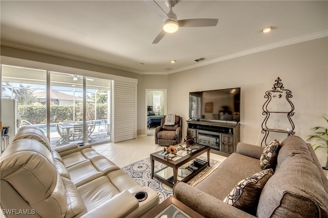 living area with light tile patterned floors, visible vents, a ceiling fan, a fireplace, and ornamental molding