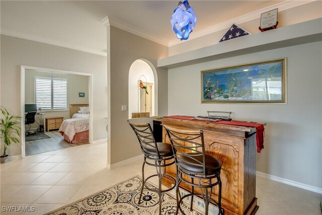 bar featuring baseboards, light tile patterned floors, arched walkways, and ornamental molding