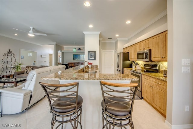 kitchen with open floor plan, appliances with stainless steel finishes, a kitchen bar, and a sink
