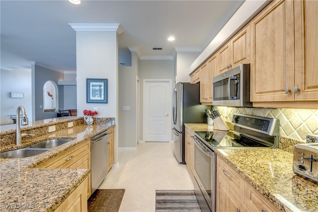 kitchen with appliances with stainless steel finishes, light brown cabinets, ornamental molding, and a sink
