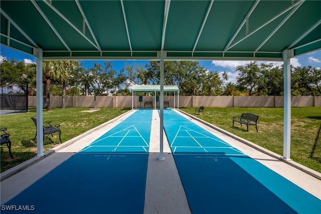 view of home's community with fence, a yard, and shuffleboard