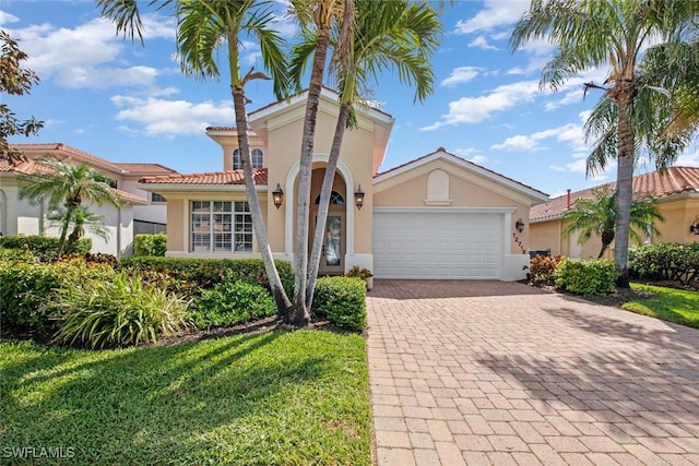 mediterranean / spanish-style house featuring a tile roof, a garage, decorative driveway, and stucco siding
