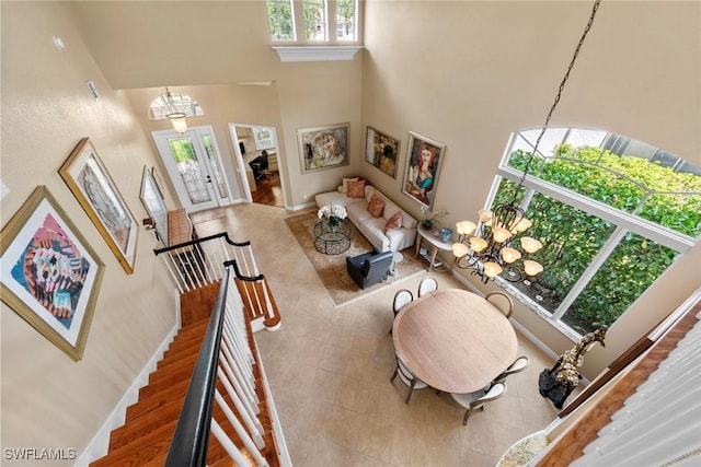 living room featuring a high ceiling, a notable chandelier, baseboards, and stairway